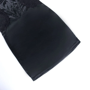 Gros plan détaillé sur la dentelle noire et le tissu en satin lisse de cette robe courte