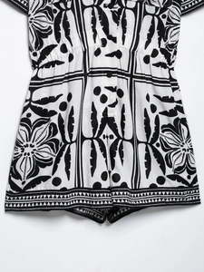 Detail of black and white romper featuring elastic waist, floral print and geometric lace edge