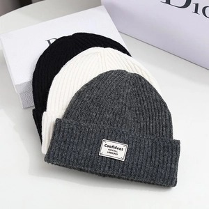 Detailed close-up of ribbed knit beanies in black, white and grey with stylish patch