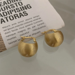 Macro shot of minimalist gold S925 silver stud earrings with a matte brushed texture