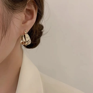 Close-up of golden vintage twisted knot earrings worn by a model in a soft lighting
