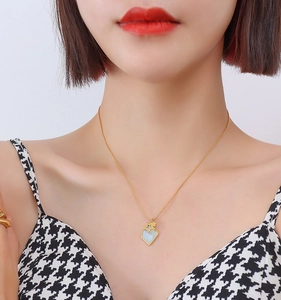 Gros plan d'un collier pendentif cœur et étoile dorée avec incrustation bleu clair