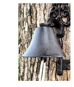Close-up of vintage cast iron doorbell bell with rustic metal texture and white rope