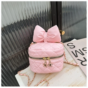 Close-up of pink quilted crossbody bag featuring a large bow and gold flower zippers