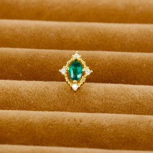 Macro shot of gold earring with emerald green zircon and micro-inlaid diamonds
