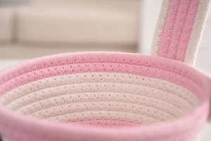 Detail eines rosa und beigen Korbes aus Baumwollseil mit Webstruktur und Griff