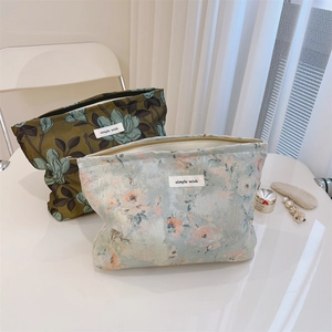 Detailed macro of two floral jacquard cosmetic bags with a metal zipper and simple label