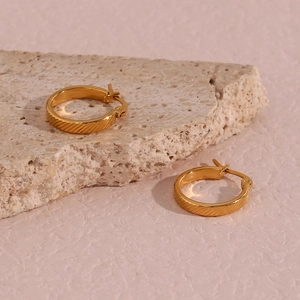 Close-up of 20mm gold-plated stainless steel hoop earrings with diagonal textured stripes