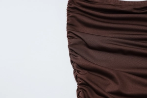 Detail view of the shirred side seam and rich coffee brown knit fabric on the dress