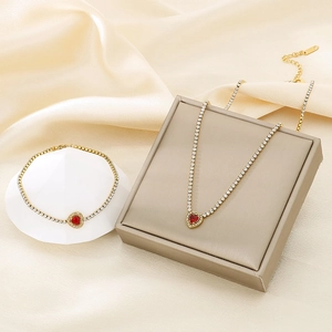 Detail of gold tennis chain necklace and bracelet set with red heart zircon pendants
