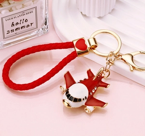 Close-up of red braided rope keychain with rhinestone airplane and heart charm
