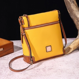 Detail of yellow lychee grain leather crossbody bag with brown trim and dual zippers