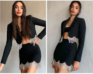 Detail of black blazer and mini skirt set featuring shimmering silver rhinestone fringe trim