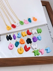 Nahaufnahme der bunten 3D-Buchstabenanhänger mit Goldöse auf einer Spiegelfläche