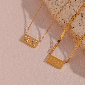 Detail of gold rectangular 11:11 pendants with zircon inlay on a textured stone base