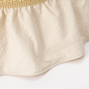 Detailed macro view of the embossed floral fabric and woven straw brim on the sun hat