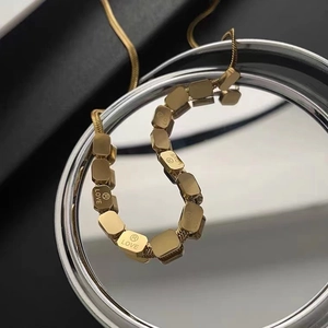 Macro view of gold snake chain necklace featuring square blocks engraved with LOVE letters