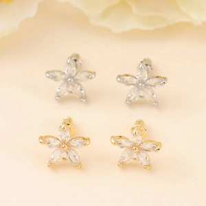 Close-up of star-shaped stud earrings in gold and silver finish with zircon stones