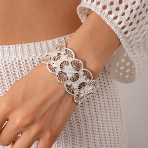 Close-up of wide silver cuff bracelet with intricate lace patterns and tiny zircons