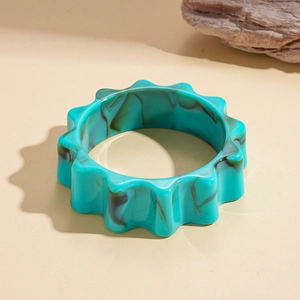 Teal marble acrylic flower gear bracelet with wavy edges on a beige background