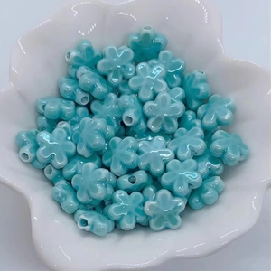 Dettaglio di perline a forma di fiore in ceramica blu cielo in una ciotola bianca per DIY