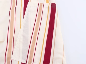 Détail de la texture rayée du tissu montrant les coutures de la poche en bordeaux et beige