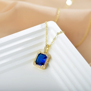 Close-up of gold titanium necklace with rectangular blue gemstone and zircon pendant