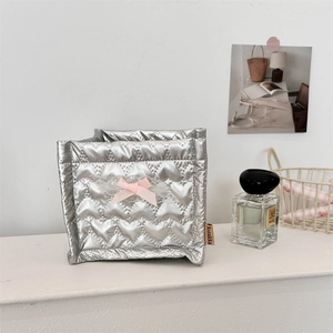 Detailed macro view of silver heart-quilted storage box with a pink lace bow and branding