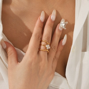 Detailed view of layered gold flower ring with zircon stones worn on model's finger