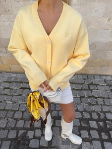 Close-up of light yellow knit cardigan featuring V-neck and delicate tonal embroidery