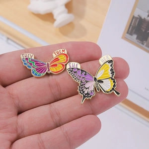 Pins papillons en émail avec pronoms SHE/HER et THEY/THEM et motifs colorés en dégradé