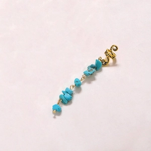 Detail of golden spiral hair ring with natural turquoise stone pendant in ethnic style