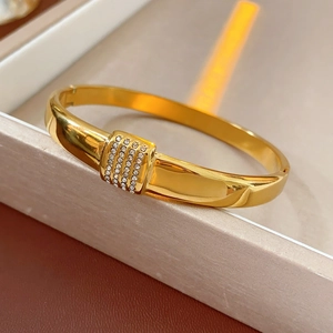 Gros plan d'un bracelet en acier titane doré avec quatre rangées de cristaux blancs