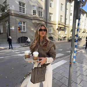 Borsa a mano in pelle grigio scuro con giacca sciancrata e pantaloni bianchi chic