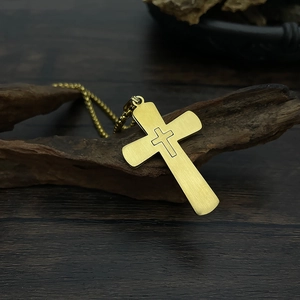 Close-up of golden double cross pendant on dark wood textured surface with focused lighting