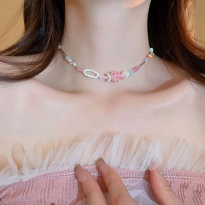 Close-up of a sweet colorful beaded choker with a strawberry pendant on model neckline