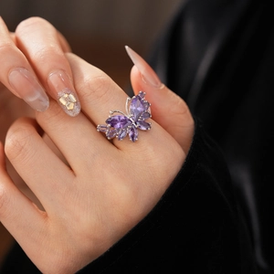 Détail de la bague papillon argentée avec cristaux de zircon violets sur le doigt