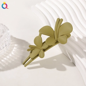 Close-up of a matte green butterfly-shaped hair clip on a minimalist white wavy texture background