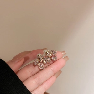 Detailopname van gouden bloemenoorbellen met kristallen en witte parelsluiting