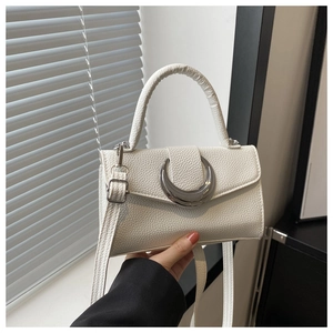 Détail du sac blanc texturé avec un fermoir croissant en métal argenté et une bandoulière