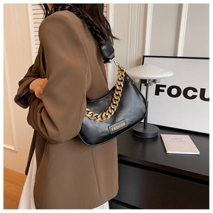 Detail of black crescent shoulder bag with chunky gold chain and fashion label
