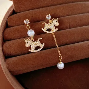 Gold-plated asymmetric rocking horse earrings with zircon and pearls on velvet