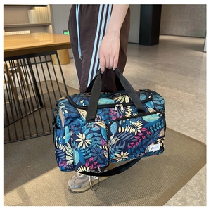 Detail of blue floral travel bag featuring vibrant leaf prints and functional pockets