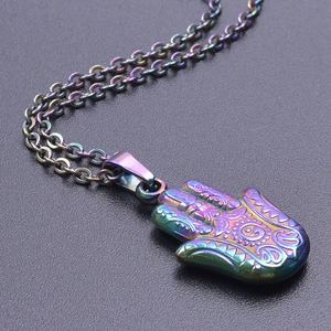 Macro d'un pendentif main de fatma iridescent avec gravures florales sur fond noir mat