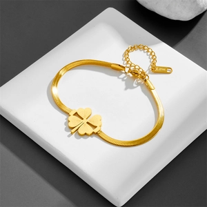 Gold stainless steel four-leaf clover bracelet with snake chain on white stone stand