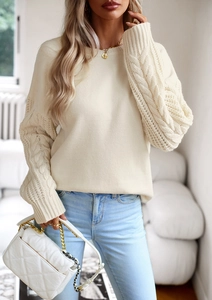 Dettaglio di maglia a trecce su maglione beige a girocollo con borsa bianca a catena