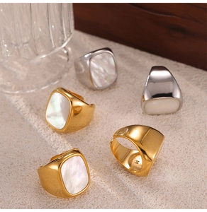 Detail of gold and silver steel rings with white shell inlay and M letter engraving