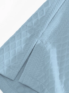 Detailed close-up of light blue waffle texture fabric with reinforced side slit stitching