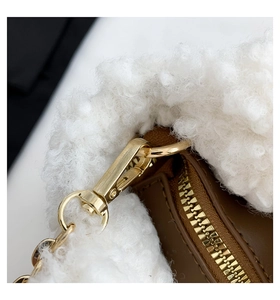 Detail of brown faux leather bag with white plush trim and glossy gold metal hardware