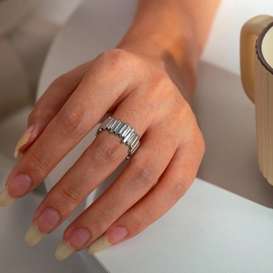 Close-up of a silver geometric leaf ring featuring a hollow multi-layer design on a finger
